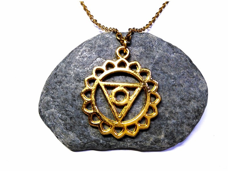 Pendentif doré avec motif géométrique du 5ème chakra. Ce yantra aide à dissiper les non-dits et à purifier les échanges.
